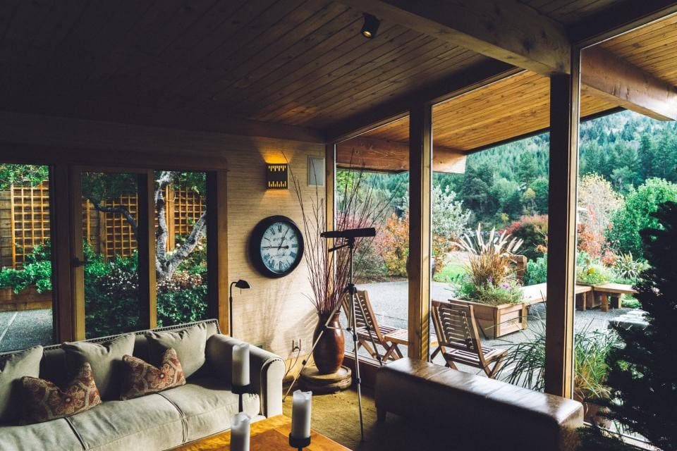 Covered outdoor living area with a timber ceiling, sofa and garden views