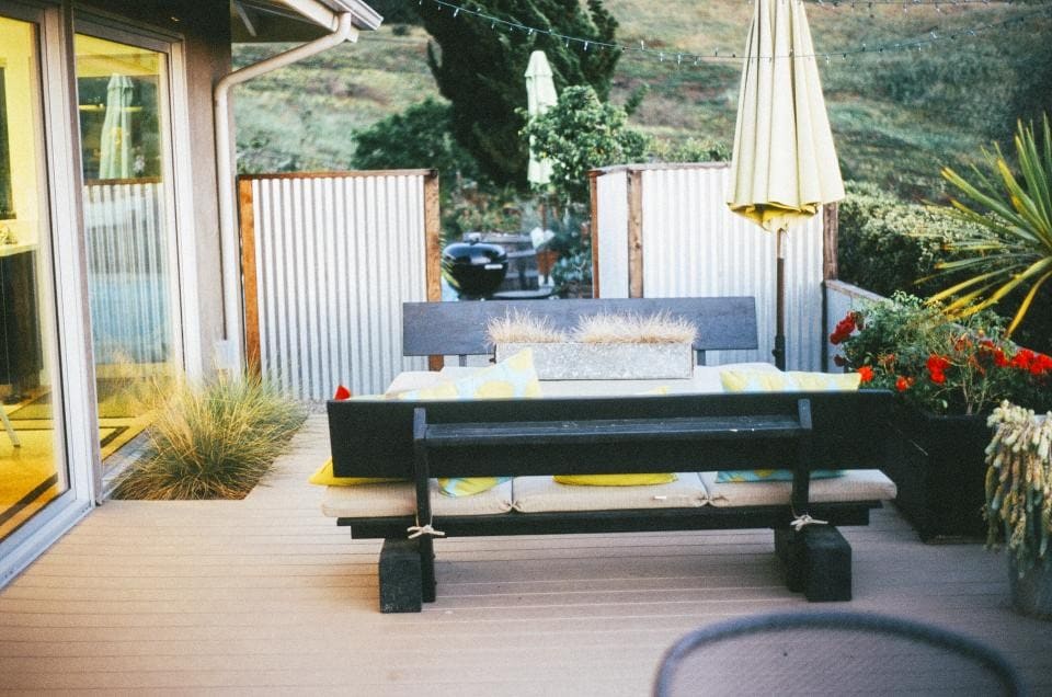 Backyard deck with an outdoor dining table, lounge bench and planters